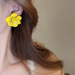 Detailed view of handmade yellow fabric flower earrings with center pearl on a model