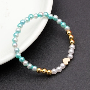 Detail of beaded bracelet with light blue pearls and gold heart pendant on black leather