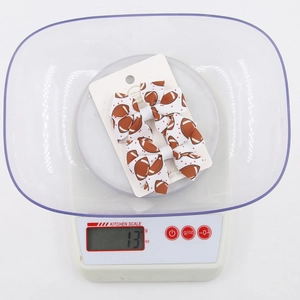 Detail view of handmade football print bow hair clips on a scale showing 13g weight