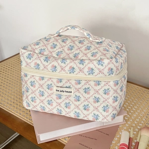 Detailed close-up of quilted floral makeup bag with blue and pink flowers on book desk