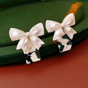 Gros plan de boucles d'oreilles nœud nacré avec base rectangulaire tachetée sur velours
