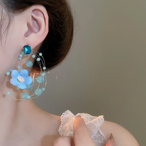 Close-up of floral tassel earrings with blue fabric petals and beaded crystal details