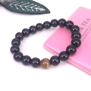Detalle de la pulsera de cuentas de hematita negra con una piedra de ojo de tigre central