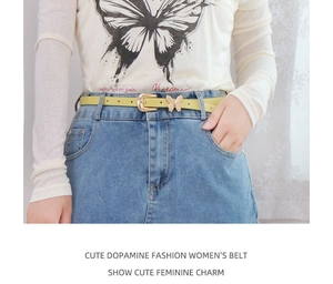 Close-up of light green leather belt with golden butterfly buckle worn on denim skirt