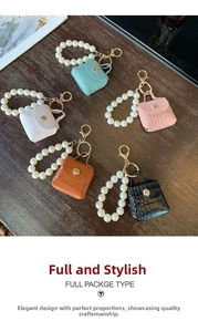 Macro detail of mini PU leather bag charms with crocodile texture and pearl wrist straps