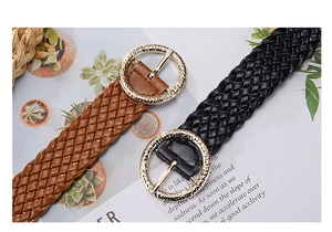 Detail of brown and black woven PU leather belts with decorative gold round buckles