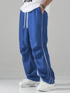 Side view of royal blue wide-leg track pants with double white stripes and drawstring waist