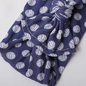 Detail of navy blue baby headband with white volleyball print and soft knot bow