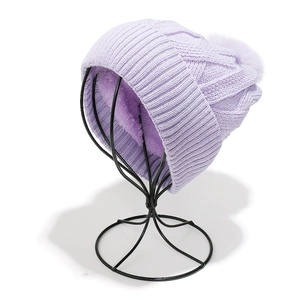 Detail view of purple knitted beanie with thick fleece lining and faux fur pompom