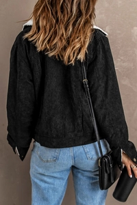 Close-up of black corduroy jacket showing white faux fur collar and textured fabric