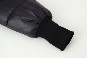 Detail of ribbed knit cuffs on a glossy black quilted winter coat for wind protection