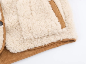 Close-up of off-white sherpa and brown suede fabric detail on a reversible jacket