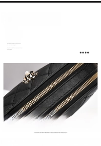 Detail of black quilted shoulder bag with gold zipper and decorative pearl flower charm