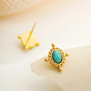Macro detail of vintage 18K gold earrings with oval turquoise inlay and beaded border