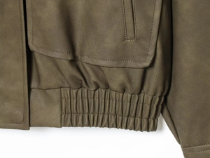 Vue détaillée de la veste en cuir vert armée montrant l'ourlet élastique et la couture
