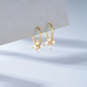 Macro view of gold S925 silver earring with clover pendant set with clear gemstones