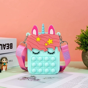 Detail of mint green unicorn pop-it purse with pink polka dot strap on a desk