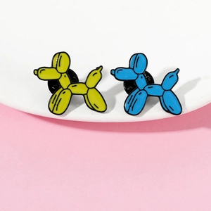 Macro shot of yellow and blue balloon dog enamel pins on a white plate edge