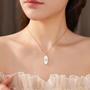 Close-up of vintage gold oval pendant with white pearl inlay on model neck