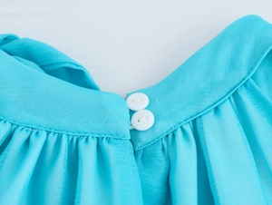 Close-up of cyan chiffon halter dress showing dual button closure and pleated texture details