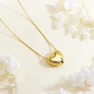 Detail of 18K gold plated heart pendant necklace on a refined textured background