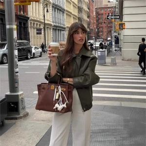 Giacca vintage in finta pelle marrone abbinata a una borsa a mano in stile classico
