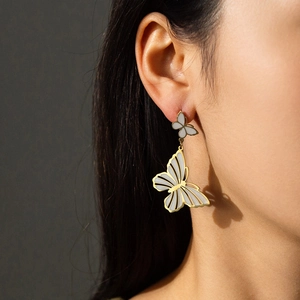 Elegant gold titanium steel double butterfly tassel earrings worn by a model