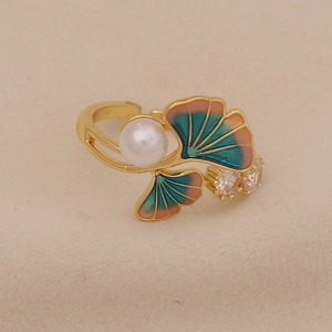 Close-up of ginkgo leaf ring with pearl and green enamel on beige fabric