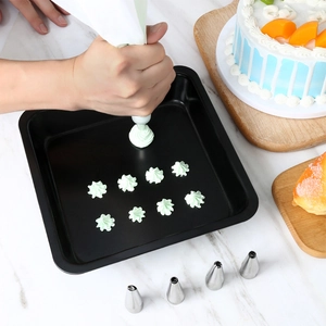 Detail of hand piping star-shaped cookies onto baking sheet with stainless steel nozzle