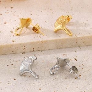 Detailed view of ginkgo leaf stud earrings in gold and silver finish with fine texture