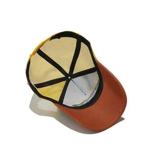 Detail view showing interior mesh structure and embroidery on orange trucker hat