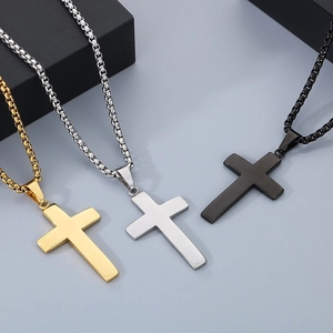 Close-up of three stainless steel cross necklaces in gold, silver, and black on box chains