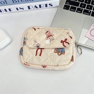 Close-up of quilted floral organizer bag with cartoon bear print on white desk setup