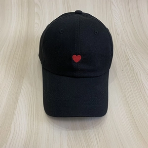 Classic black cotton baseball cap with red heart embroidery on light wood background
