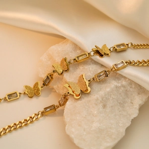 Chic gold butterfly bracelet with zircon stone on white stone and silk background