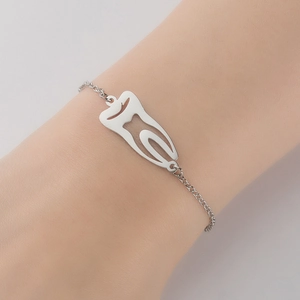 Minimalist silver tooth pendant bracelet with fine cross chain on woman's wrist
