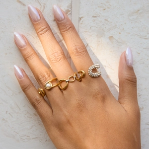 Détail de bagues superposées plaquées or 18 carats avec perles et strass sur modèle