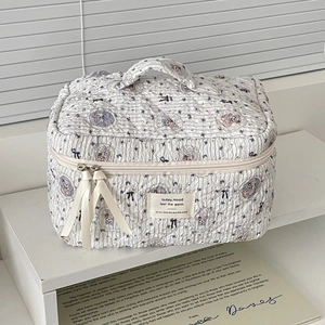 Detail of quilted bear makeup bag with floral patterns, ribbon zipper, and top handle