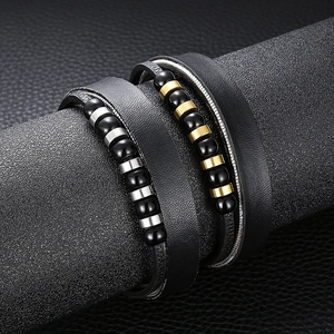 Detail of double-layer black leather bracelet featuring metallic beads on a textured stand