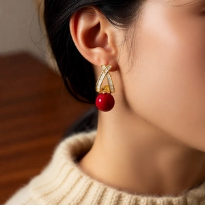 Macro shot of gold plated earrings with red round pendants and sparkling zircon stones