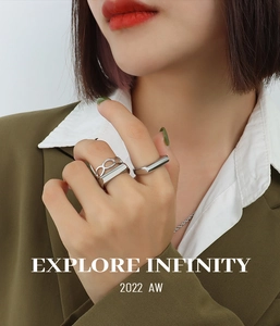 Macro view of minimalist silver geometric rings worn by a model in green blazer