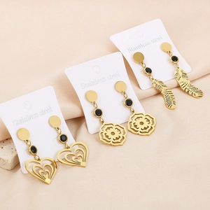 Détail de boucles d'oreilles en acier doré aux motifs cœur, fleur et plume ajourés