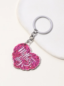 Close-up of heart-shaped keychain with pink roses and Happy Mother's Day text on wood