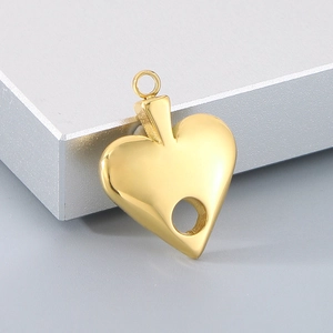 Macro shot of gold hollow heart pendant on matte silver pedestal with metal shine