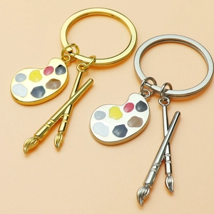 Artistic keychain with colorful palette and paintbrushes in gold and silver finish