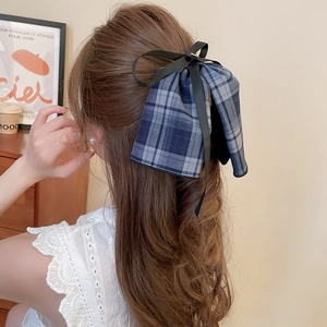 Detail of blue plaid fabric bow hair clip with black ribbons styled on a ponytail