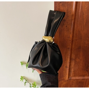 Detailed view of black gathered bucket bag featuring a large organic gold metal buckle handle