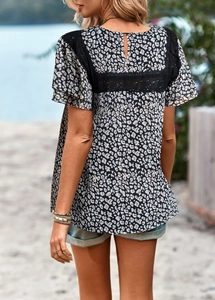 Detailed back view of vacation floral top with intricate black lace patchwork panels