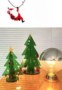 Mini green acrylic Christmas trees with a vintage decorative lamp on a wooden desktop