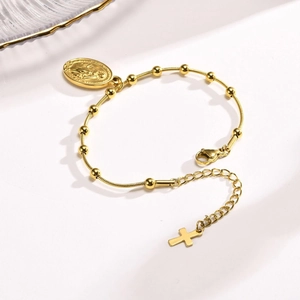 Golden stainless steel rosary bracelet with Virgin Mary medal and cross pendant on white surface